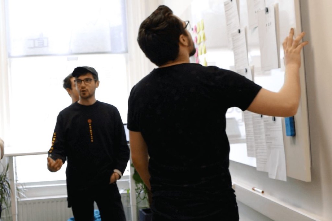 Designers pinning research onto a wall in the Komodo Digital studio